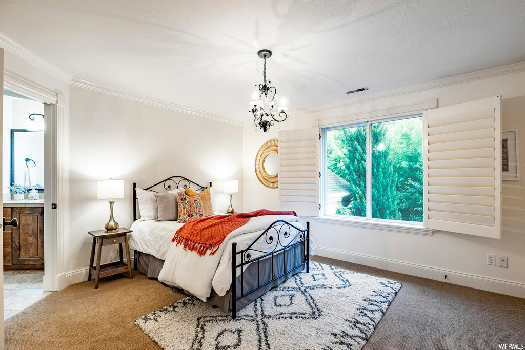 Carpeted bedroom featuring a chandelier and ornamental molding