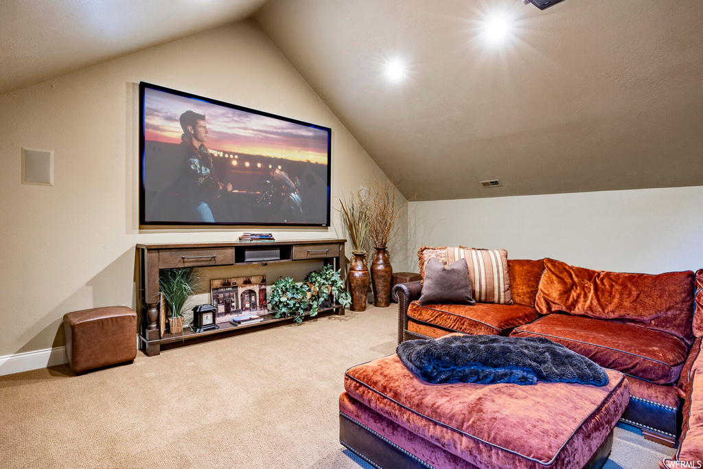 Carpeted home theater featuring vaulted ceiling