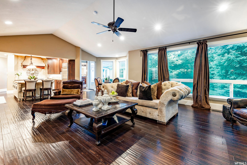 Hardwood floored living room with plenty of natural light, ceiling fan, and vaulted ceiling