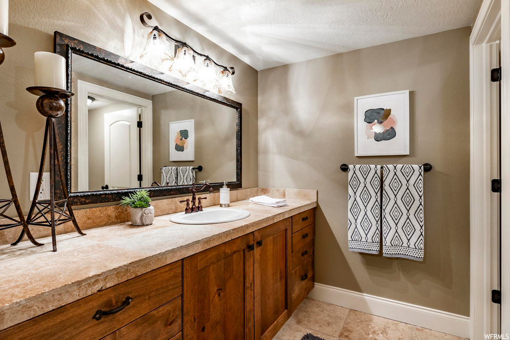 Bathroom featuring vanity, a textured ceiling, light tile floors, and mirror