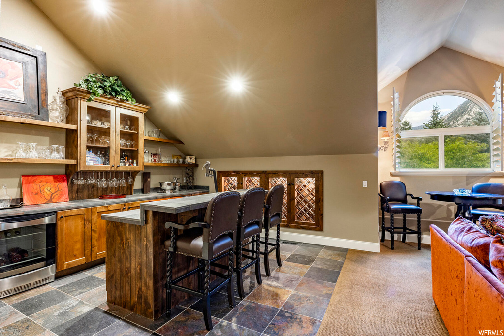 Kitchen featuring light tile floors, a center island, vaulted ceiling, and light countertops