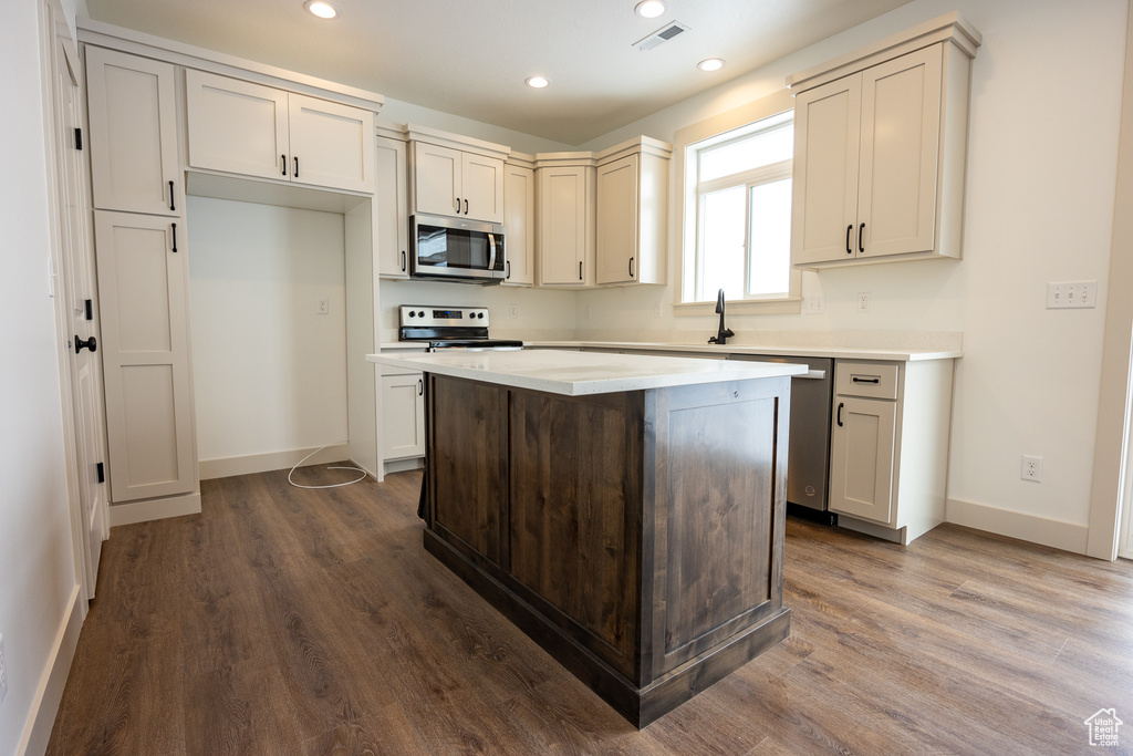 Kitchen with dark hardwood / wood-style flooring, appliances with stainless steel finishes, and a center island