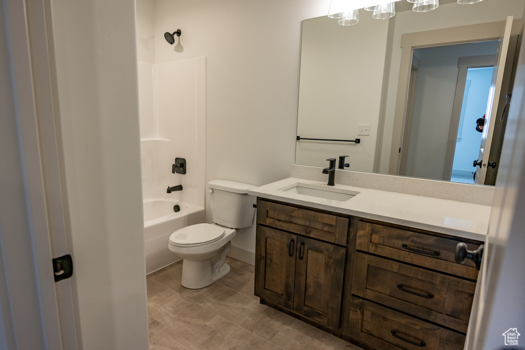 Full bathroom with tile flooring, vanity, toilet, and washtub / shower combination