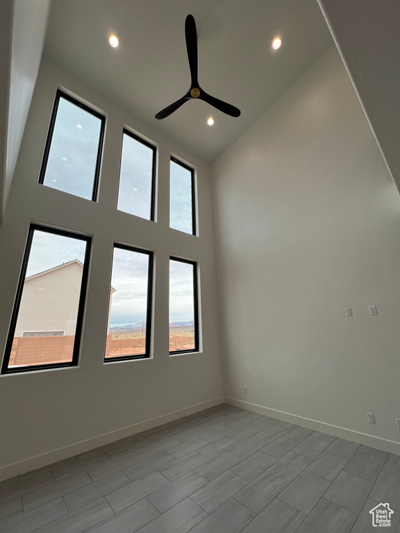 Spare room with a wealth of natural light, a high ceiling, and ceiling fan