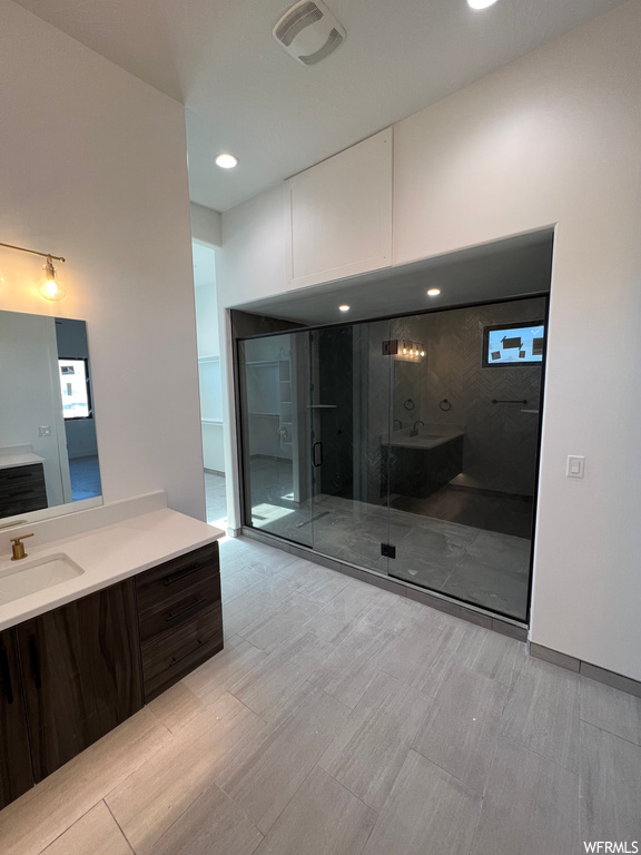 Bathroom featuring a shower with shower door and vanity with extensive cabinet space