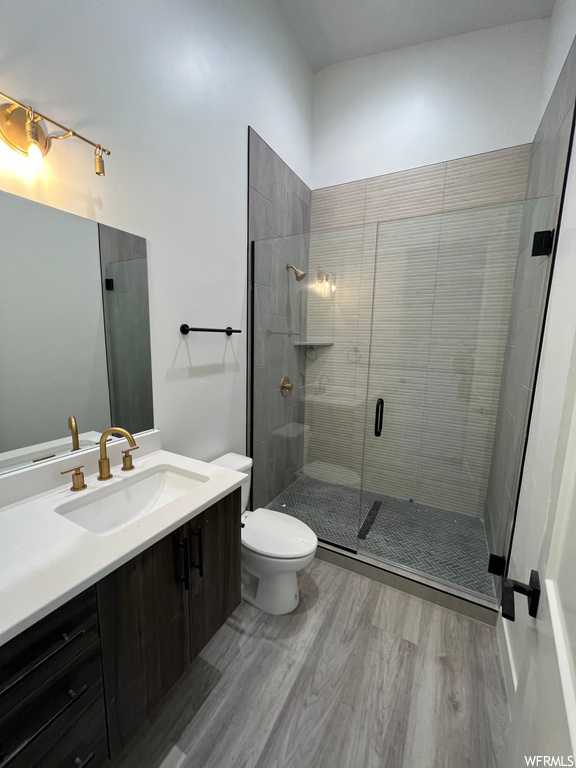 Bathroom featuring toilet, hardwood / wood-style floors, a shower with shower door, and vanity