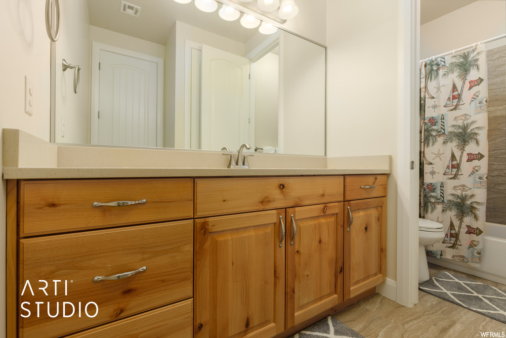 Full bathroom with vanity, shower / bath combo, light hardwood flooring, and mirror