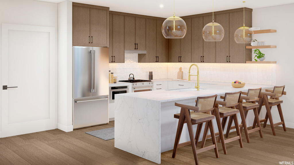 Kitchen featuring pendant lighting, high end refrigerator, backsplash, white range, light countertops, a center island, and light hardwood floors