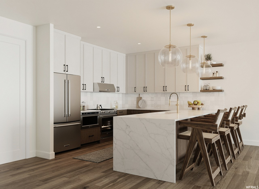 Kitchen with pendant lighting, white cabinets, a kitchen island, wood-type flooring, stainless steel built in fridge, and backsplash