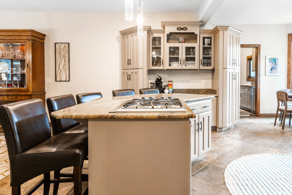 Kitchen with stainless steel gas stovetop, light countertops, light tile floors, and a kitchen island