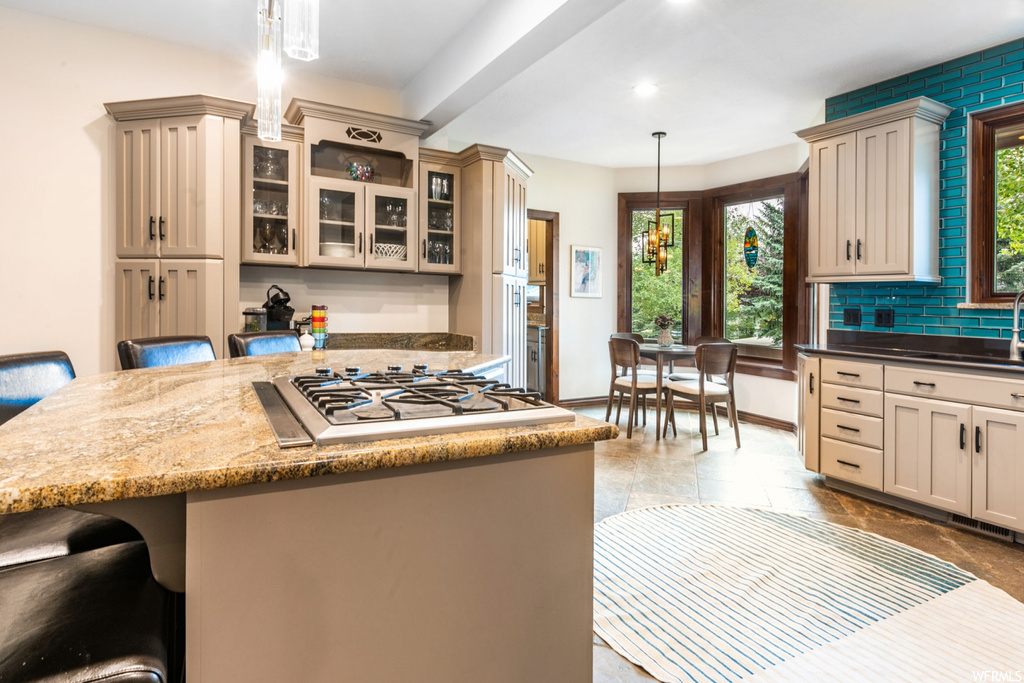 Kitchen featuring light tile floors, white gas cooktop, and dark stone counters