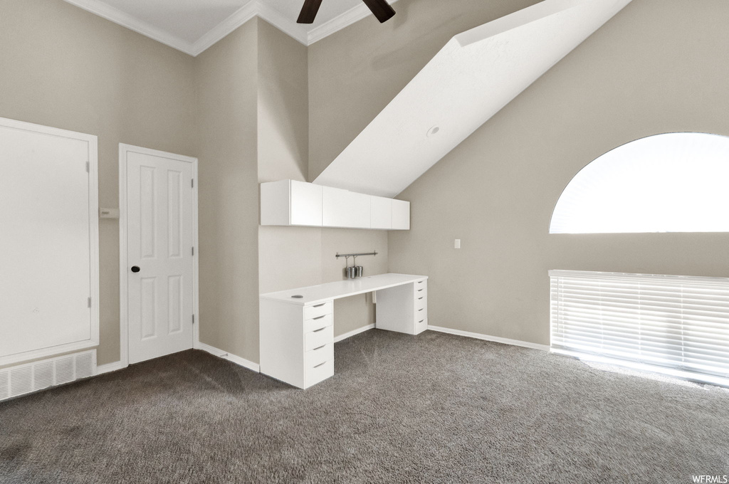 Carpeted office featuring ornamental molding, vaulted ceiling, ceiling fan, and a high ceiling