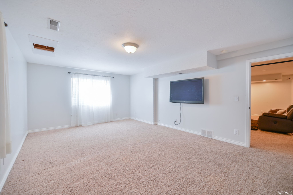 Carpeted empty room featuring a wall unit AC