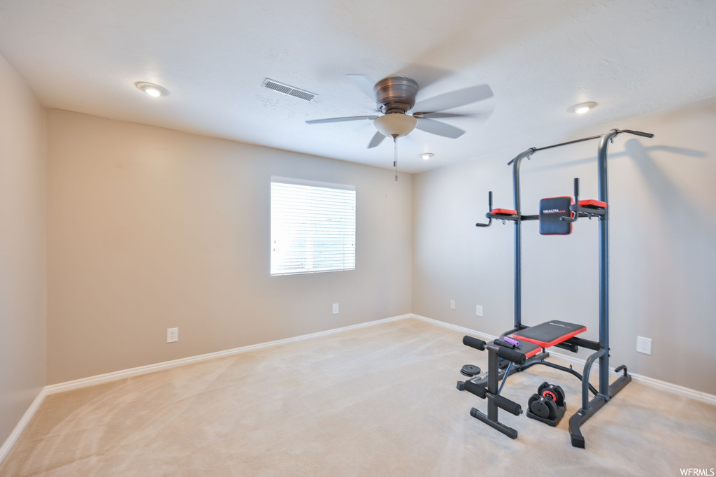 Workout room with ceiling fan and light carpet