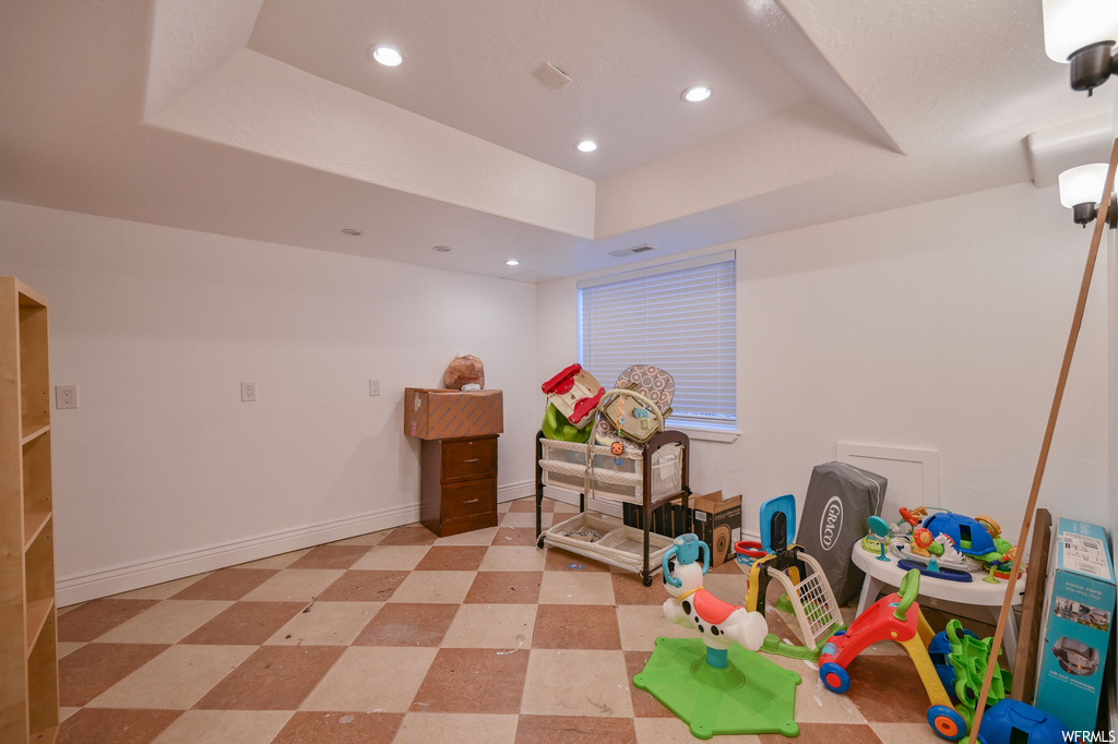 Rec room with a raised ceiling and light tile floors