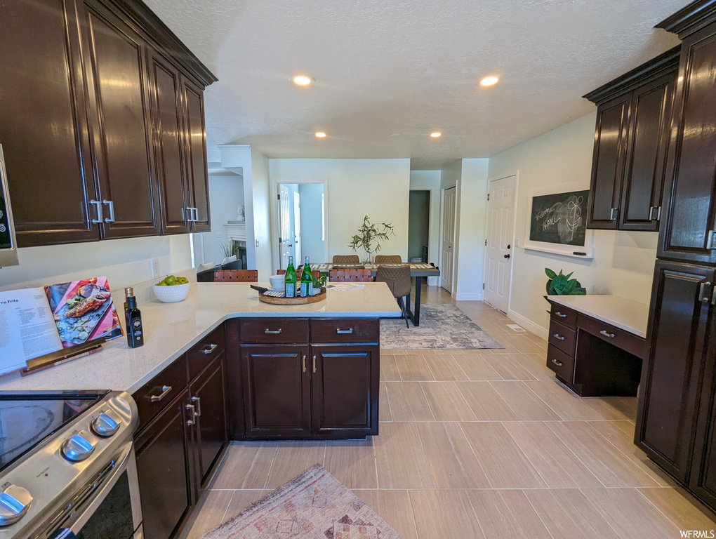 Kitchen featuring dark brown cabinets, light countertops, range, and light tile floors