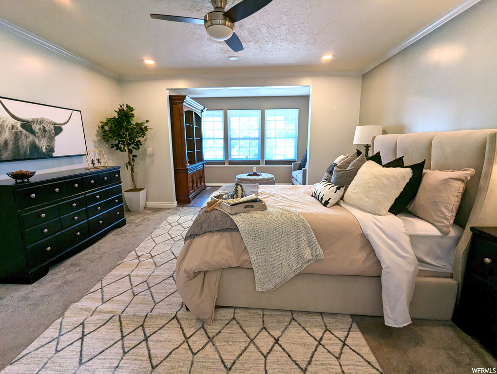 Bedroom with crown molding, light carpet, a textured ceiling, and ceiling fan