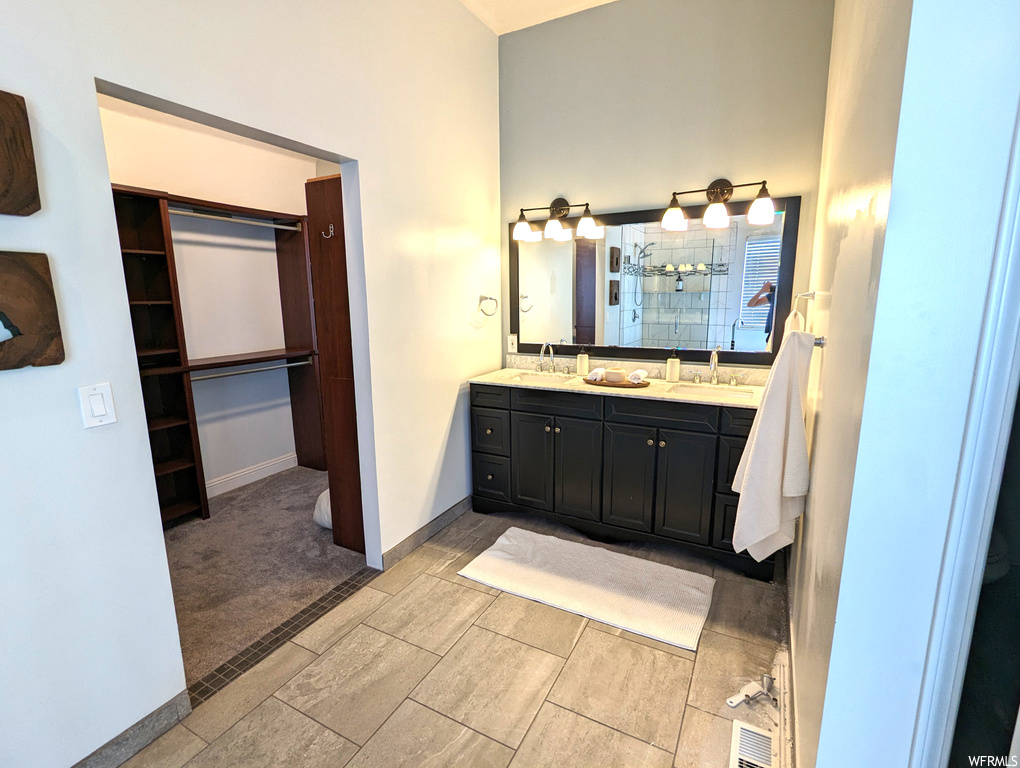 Bathroom with mirror, dual large bowl vanity, and light tile floors