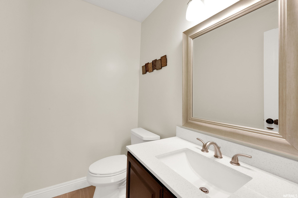 Bathroom with large vanity, hardwood floors, and mirror