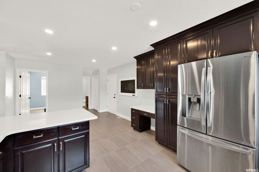 Kitchen with light tile floors, light countertops, stainless steel refrigerator with ice dispenser, and dark brown cabinetry