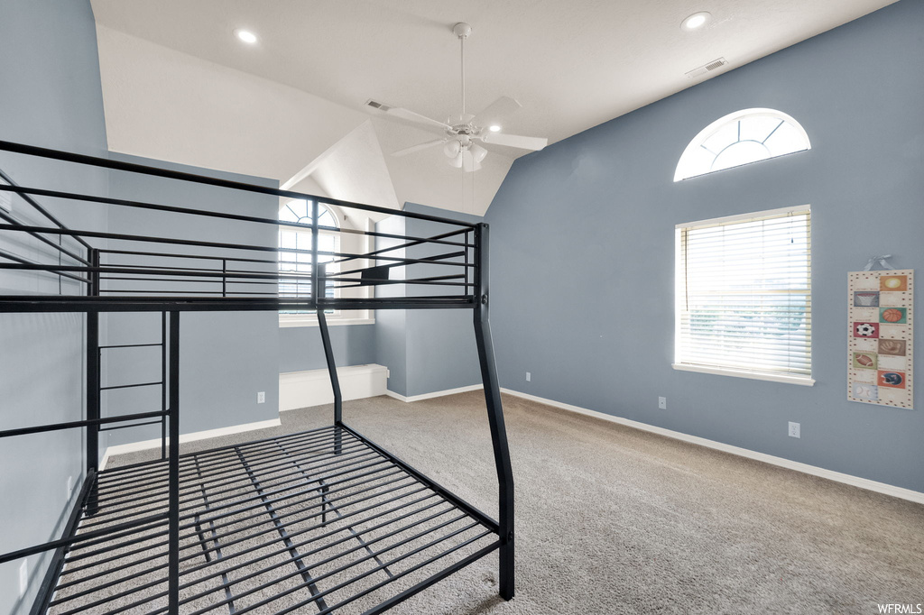 Carpeted bedroom with ceiling fan and a high ceiling