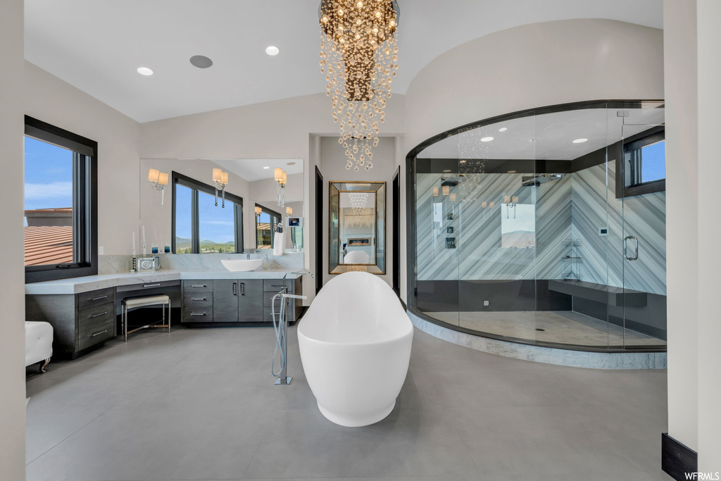 Bathroom featuring shower with separate bathtub, vanity, and a notable chandelier
