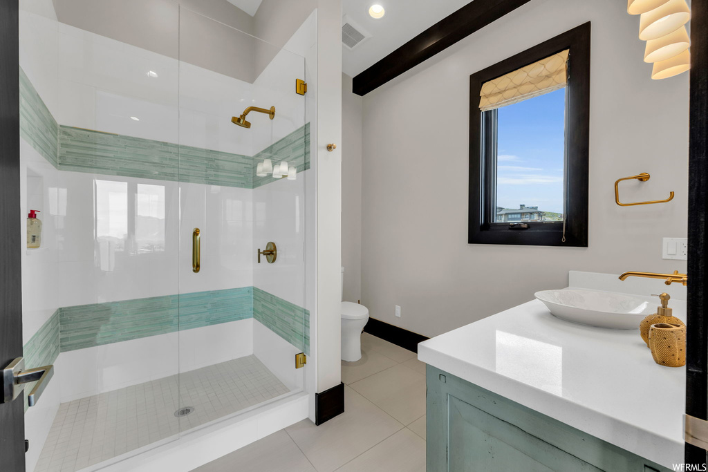 Bathroom with light tile floors, beam ceiling, vanity, and a shower with door