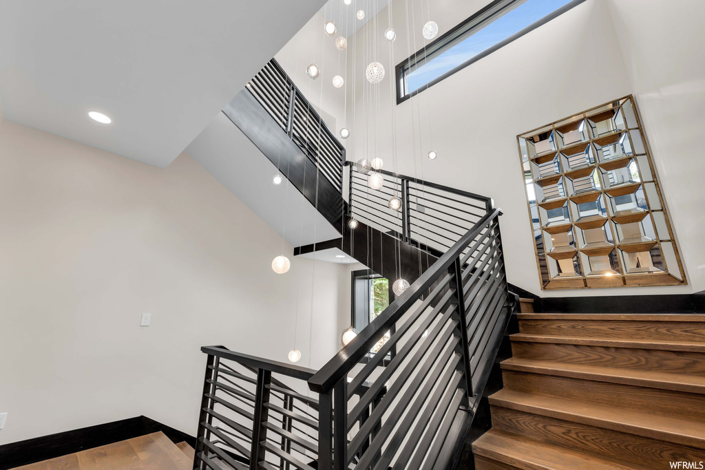 Stairs with a skylight, dark hardwood floors, and a high ceiling