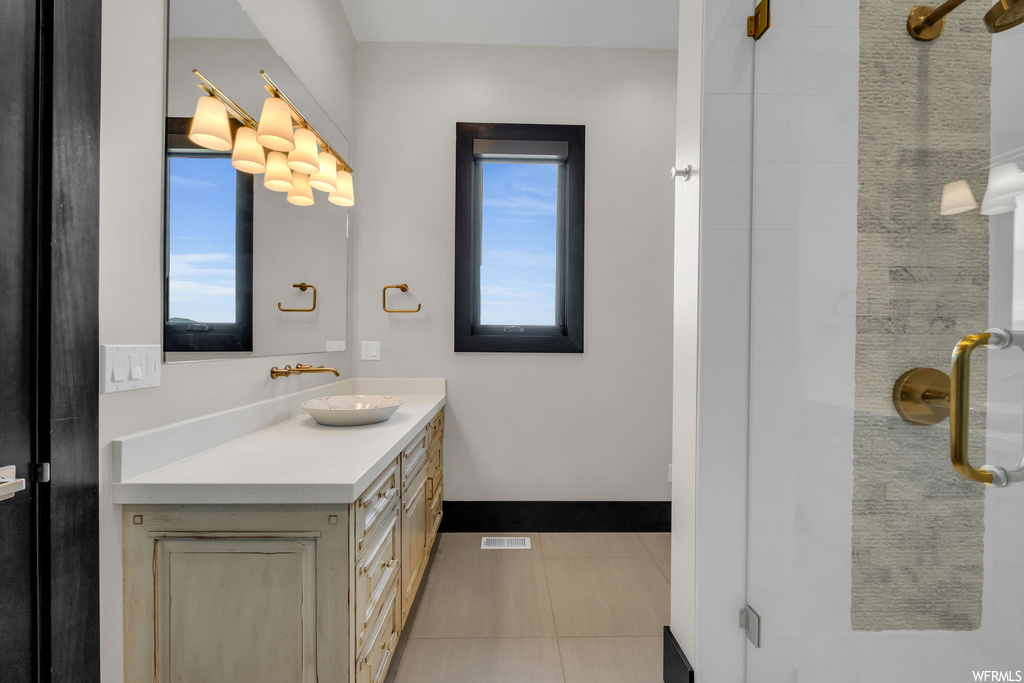Bathroom with a healthy amount of sunlight, vanity, tile floors, and mirror