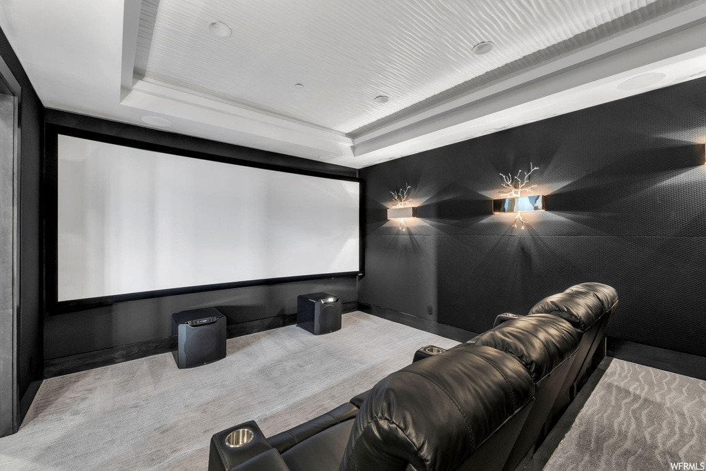 Carpeted home theater room featuring a tray ceiling