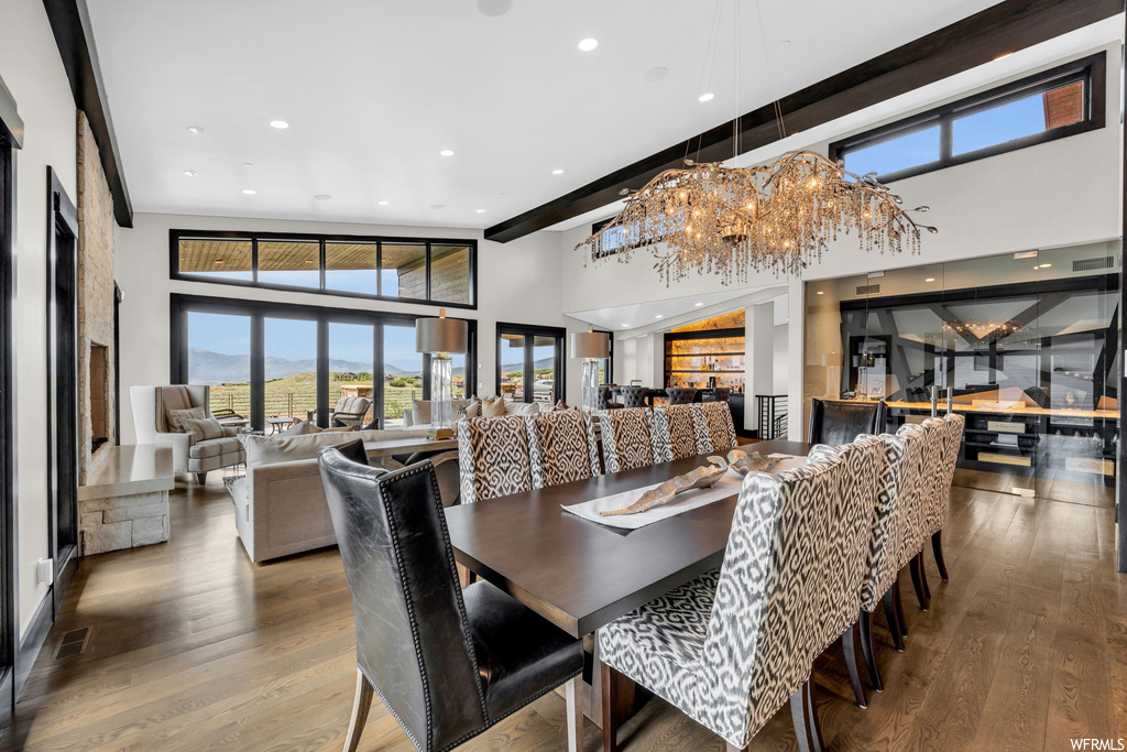 Dining space featuring light parquet floors, beam ceiling, a high ceiling, and a notable chandelier