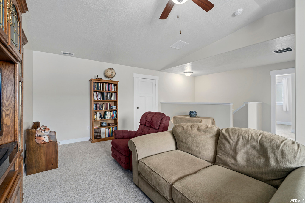 Living room with lofted ceiling, ceiling fan, and light carpet