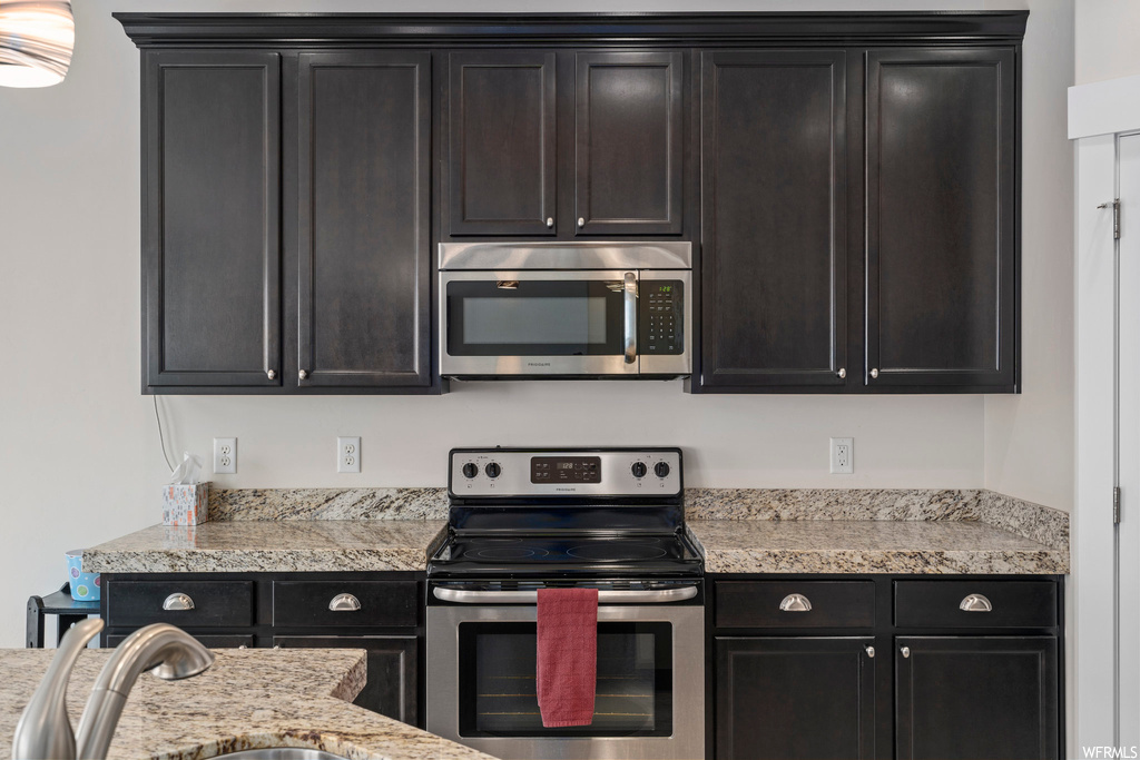 Kitchen with light granite-like countertops, appliances with stainless steel finishes, and dark brown cabinetry