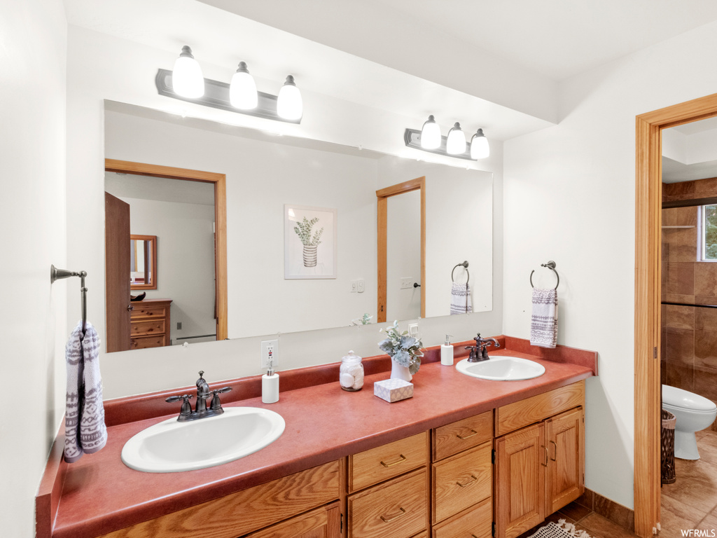 Bathroom with dual bowl vanity, mirror, and tile floors