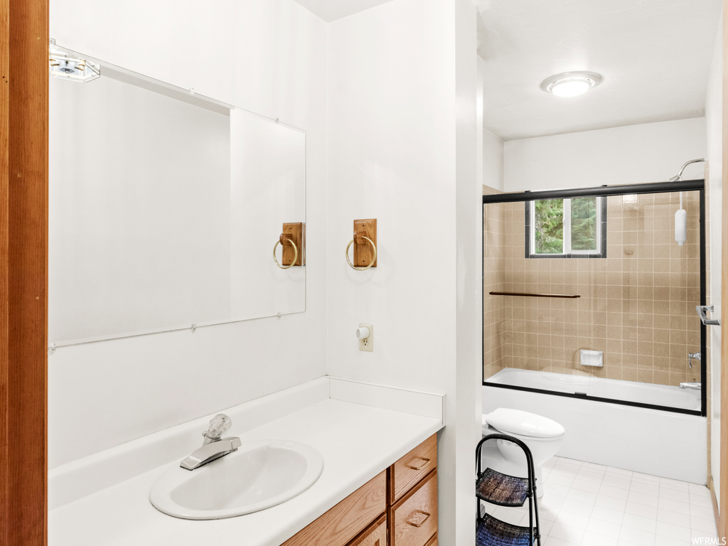 Full bathroom featuring vanity, combined bath / shower with glass door, light tile flooring, and mirror