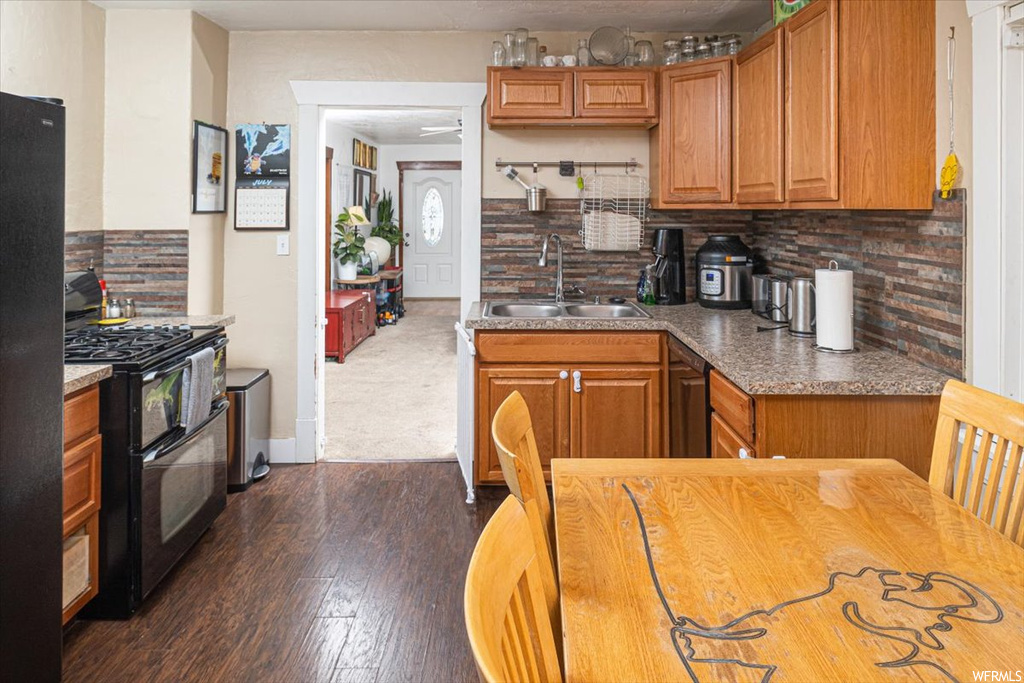 Kitchen featuring light carpet, brown cabinets, black range with gas cooktop, and backsplash