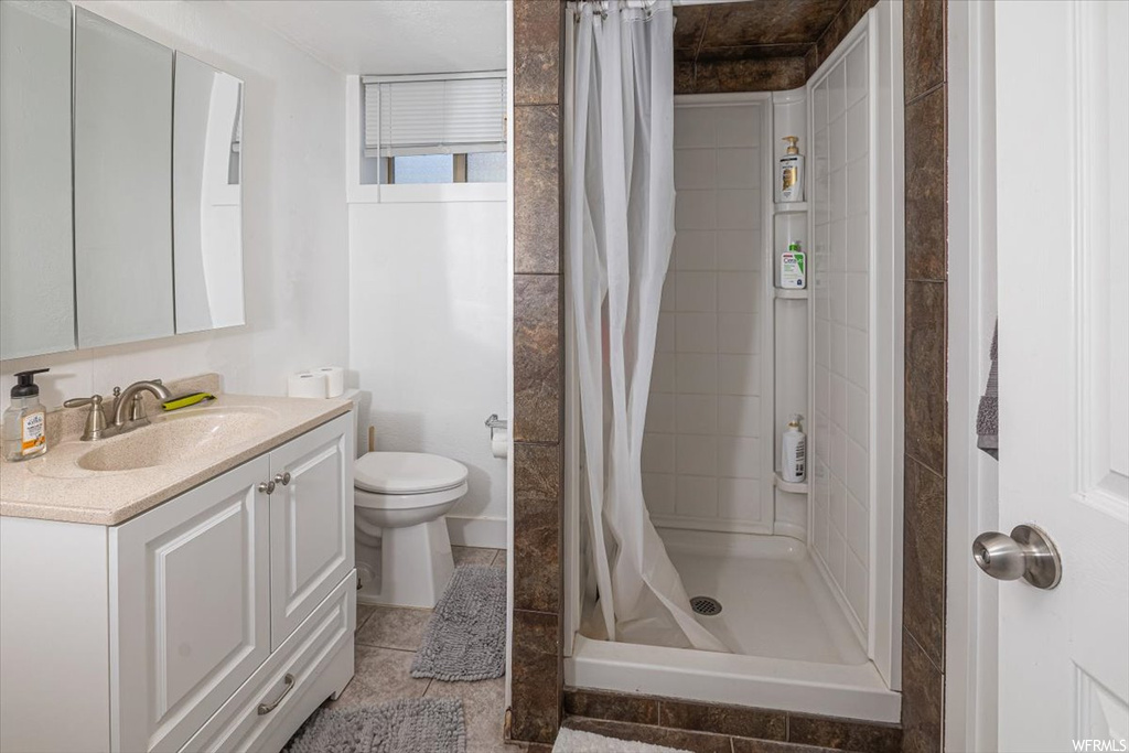 Bathroom with tile flooring, a shower with curtain, vanity with extensive cabinet space, and mirror