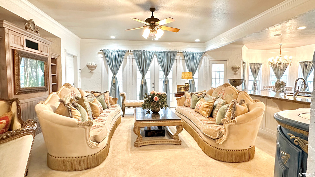 Living room featuring ornamental molding and ceiling fan with notable chandelier