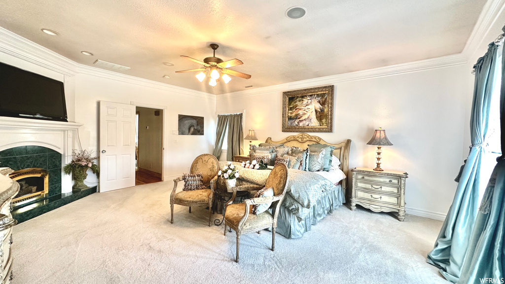 Carpeted bedroom featuring a fireplace, ornamental molding, and ceiling fan