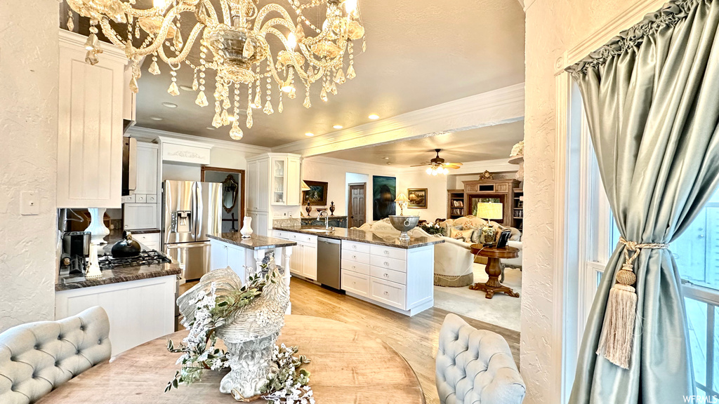 Kitchen with ceiling fan with notable chandelier, appliances with stainless steel finishes, and light parquet floors