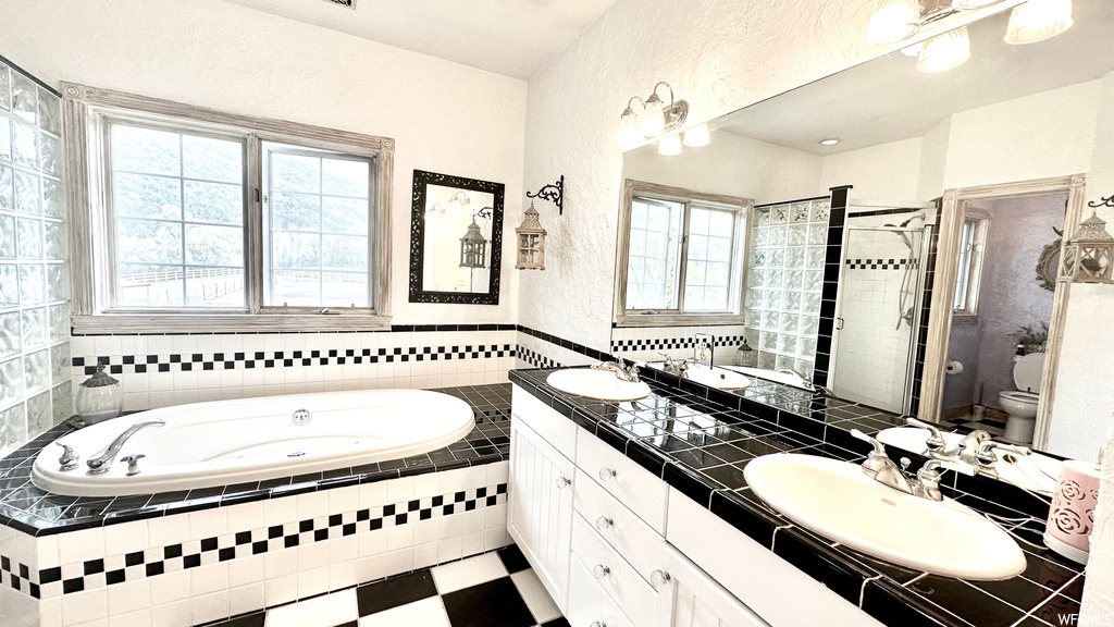 Full bathroom featuring independent shower and bath, double large sink vanity, tile flooring, and mirror