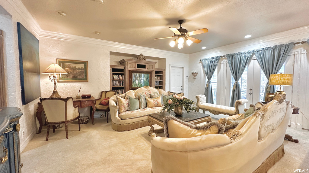 Carpeted living room featuring a textured ceiling, ornamental molding, and ceiling fan