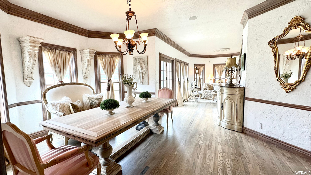 Wood floored dining space with crown molding and a notable chandelier