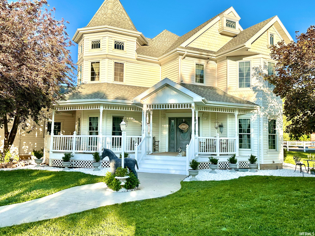 Victorian-style house featuring a front lawn and a porch
