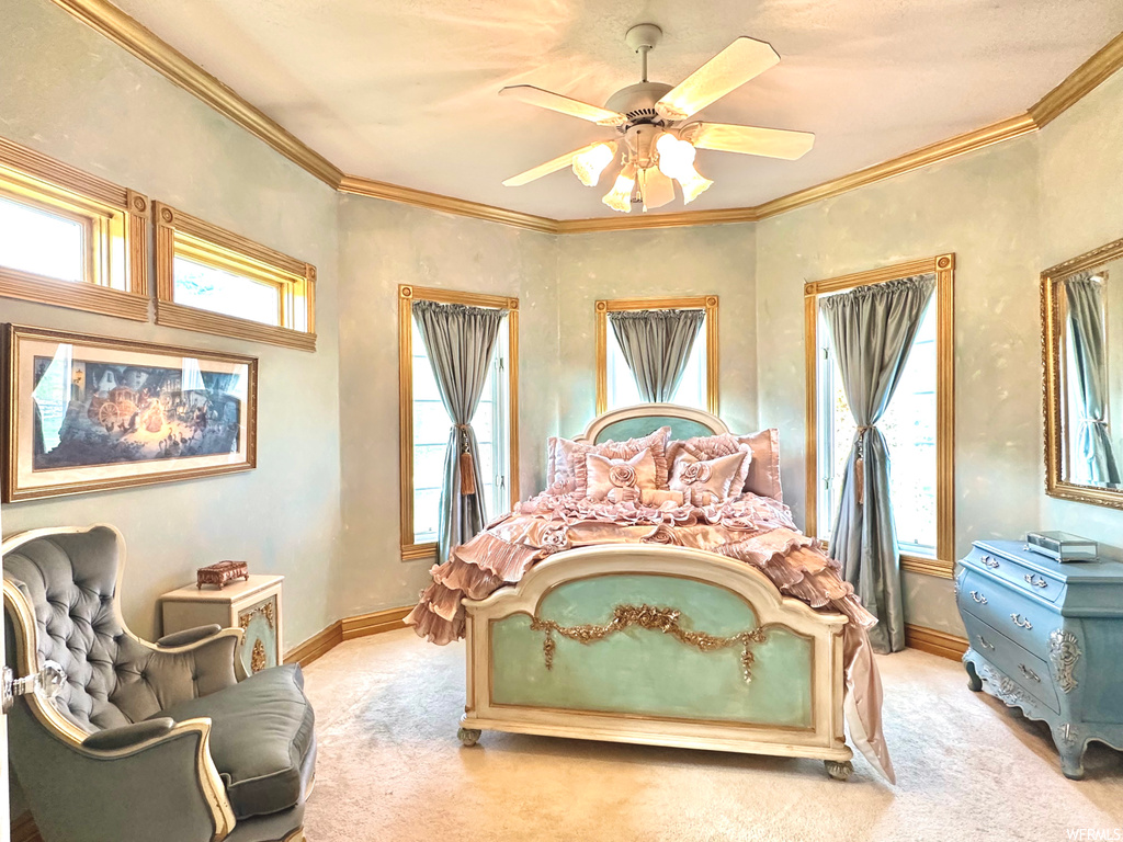 Carpeted bedroom with ornamental molding, multiple windows, and ceiling fan