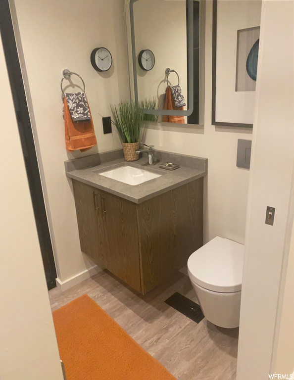 Bathroom featuring vanity with extensive cabinet space, light parquet floors, and mirror