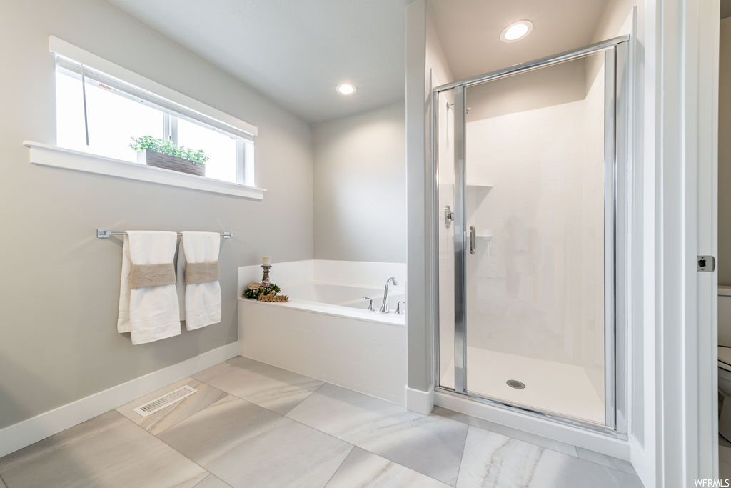Bathroom featuring separate shower and tub and light tile flooring