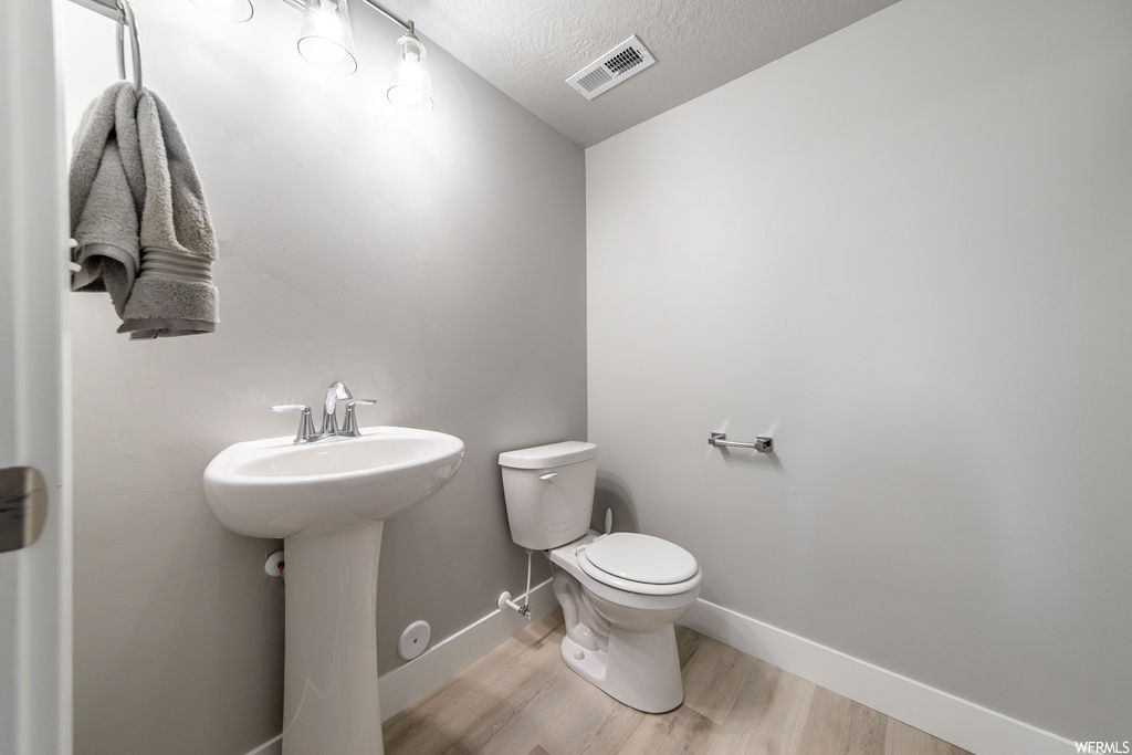 Bathroom with a textured ceiling, light hardwood flooring, and sink