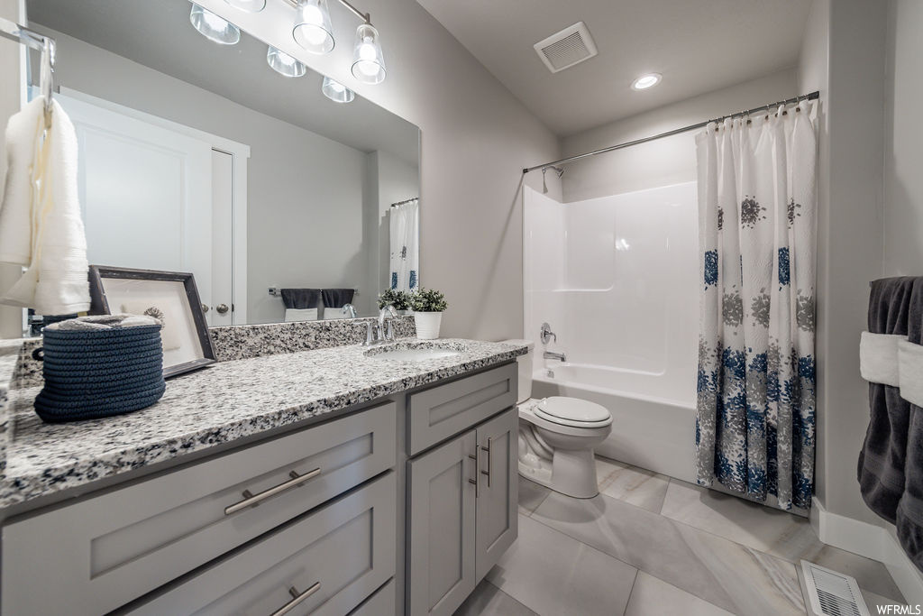 Full bathroom with light tile floors, vanity, shower / bathtub combination with curtain, and mirror