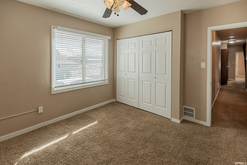 Unfurnished bedroom with ceiling fan, a closet, and carpet flooring